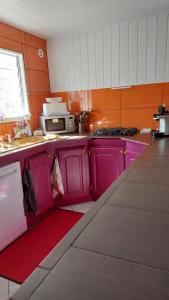 a kitchen with pink cabinets and a red counter top at Chambres chez l'habitant BOIS D'OLIVE 974 in Bois dʼOlive