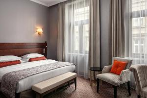a bedroom with a bed and a chair and window at COSMOPOLITAN Hotel Prague in Prague
