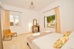 a white bedroom with a bed and a window at Baloma Apartment in Falasarna