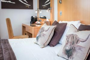 1 dormitorio con cama con almohadas y escritorio en High Range Lodge Hotel en Aviemore
