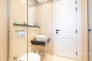 La salle de bains est pourvue d'un lavabo et d'une porte de douche en verre. dans l'établissement LUX The Bonnington JLT Suite, à Dubaï