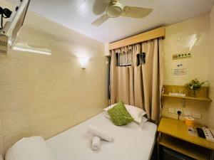 香港にあるHoliday Guest Houseのベッドとデスクが備わる小さな客室です。