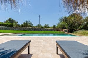 una piscina con 2 bancos en un patio en Agroturismo Cal Tio 4, YourHouse en Costitx