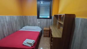 ein kleines Schlafzimmer mit einem roten Bett und einem Schreibtisch in der Unterkunft Hostal San Marcos II in Guadalajara
