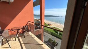 a balcony with a table and chairs and a beach at Zigrabay lovely appartments in Primorsko