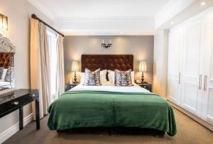 a bedroom with a large bed with a green blanket at Romney Park Luxury Apartments in Cape Town