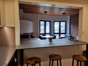 a kitchen with a bar with stools and a living room at Outdoor Hostel Laajis in Jyväskylä