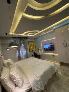 1 dormitorio con cama blanca y TV en el techo en Blissful Oasis Apartment, en Kadobunkuro
