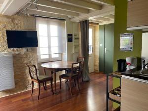 uma cozinha com uma mesa e cadeiras e uma televisão em Duplex 1er étage résidence "L'anglais" centre Bayeux grande terrasse et jardin aménagé commun proche du plages du débarquement- parking gratuit à proximité em Bayeux