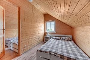 Cette petite chambre comprend un lit dans une maison en bois. dans l'établissement Domki i pokoje Angelo z sauną i jacuzzi- Karwia, à Karwia