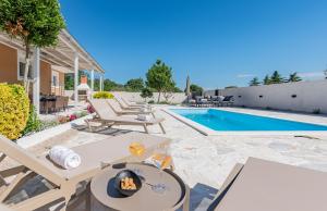 een patio met een tafel en stoelen naast een zwembad bij Holiday Home LaMar - with heated pool and whirlpool in Raštević