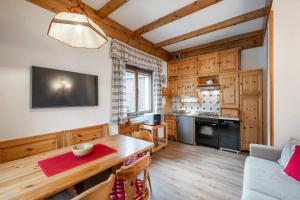 Una sala de estar con una mesa y una cocina. en Lovely 2 bedroom flat in Corso Italia with parking, en Cortina dʼAmpezzo