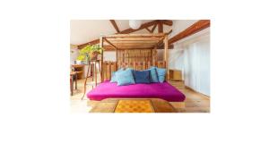 sypialnia z fioletowym łóżkiem z niebieskimi poduszkami w obiekcie Le Loft, chambre triple - Gîte de la Louve w mieście Fougax-et-Barrineuf