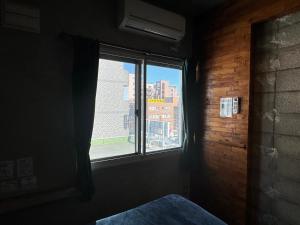 a bedroom with a window with a view of a city at Untapped Hostel in Sapporo