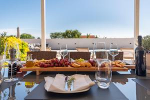 een tafel met een dienblad met eten en wijnglazen bij Holiday Home LaMar - with heated pool and whirlpool in Raštević