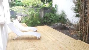 2 chaises blanches assises sur une terrasse en bois dans l'établissement Ka Villa Location, à Pointe-Noire