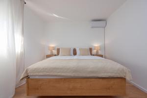 een witte slaapkamer met een bed met 2 lampen bij Holiday Home LaMar - with heated pool and whirlpool in Raštević +41 foto's