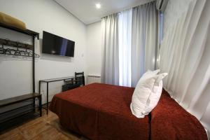 a bedroom with a bed with a red blanket and white pillows at Hostal Las Fuentes in Madrid