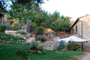 un patio trasero con un jardín con flores y una valla en Locanda All'Andreas, en Montemerano