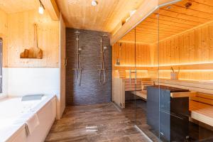ein Badezimmer mit einer Dusche, einer Badewanne und einem Waschbecken in der Unterkunft Alpenchalets Reiteralm by ALPS RESORTS in Schladming