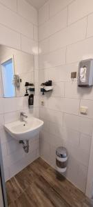 a white bathroom with a sink and a trash can at City Centre Unterkunft in Itzehoe