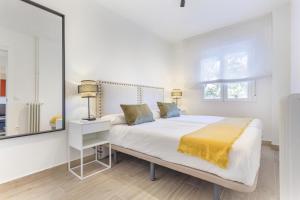 a white bedroom with a large bed with a yellow blanket at Metropolitano en Madrid in Madrid