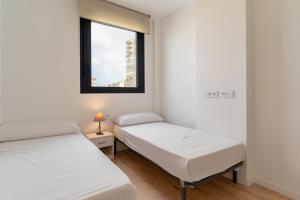 2 Betten in einem kleinen Zimmer mit Fenster in der Unterkunft GuestReady - Sunny Seaside Escape in Málaga in Málaga