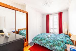 1 dormitorio con cama, escritorio y espejo en GuestReady - Modernity and comfort in Plaisance, en París