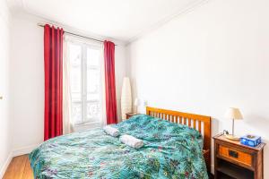 1 dormitorio con 1 cama y una ventana con cortinas rojas en GuestReady - Modernity and comfort in Plaisance, en París