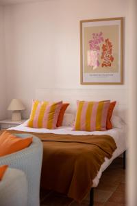 1 dormitorio con 1 cama con almohadas de color naranja y amarillo en Los Bungalows Del Arenal, en Jávea