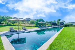 a swimming pool with chairs and umbrellas at 22 Mbali Loop, Zululami Estate in Ballito
