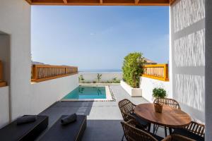 un patio al aire libre con mesa, sillas y piscina en La Torretta en Pyrgos