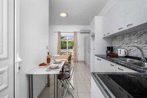 a kitchen with a sink and a table with chairs at Pervolia Studios Near Airport in Kremasti