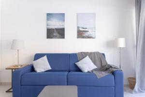 eine blaue Couch in einem Wohnzimmer mit Bildern an der Wand in der Unterkunft GuestReady - Cannes Delight near Mouré Rouge Port in Cannes