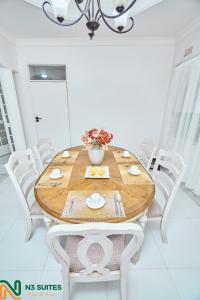a dining room with a wooden table and white chairs at The N3 Luxury Suite in Mzuzu