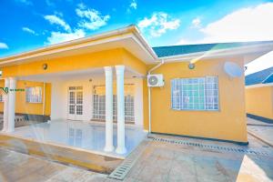 a rendering of a yellow house with columns at The N3 Luxury Suite in Mzuzu