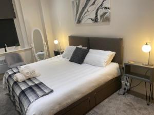 Schlafzimmer mit einem großen Bett mit weißer Bettwäsche und einem Schreibtisch in der Unterkunft Flat 2 ,559 Wimborne Road in Bournemouth