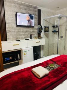 a bedroom with a bed with a television on a wall at Executive Galaxy Guest House Nkowankowa 