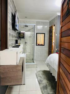 uma casa de banho com um chuveiro, uma cama e um lavatório. em Executive Galaxy Guest House Nkowankowa 