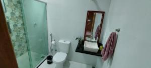 uma casa de banho com um WC, um chuveiro e um espelho. em Cantinho Top em Búzios