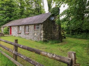 an old stone house in a field with a fence at Penyrallt Fach Cottage in Llandysul