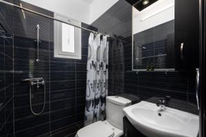 a black and white bathroom with a toilet and a sink at Pervolia Studios Near Airport in Kremasti