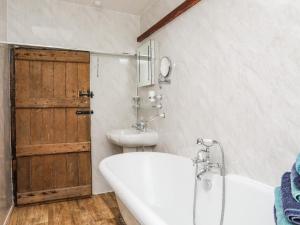 a bathroom with a tub and a sink and a door at Hendy Cottage in Llanbedr +42 photos