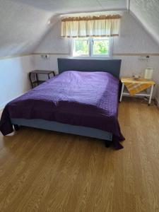 sypialnia z fioletowym łóżkiem i drewnianą podłogą w obiekcie Red cottage with a nice view of the landscape, at Aboda Klint w mieście Alsterbro