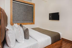 a bedroom with a bed and a window with a television at FabHotel Airport Palace in Mumbai