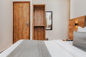 ムンバイにあるFabHotel Airport Palaceのベッドルーム1室(ベッド1台付)、木製のドア