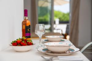 a table with a bottle of wine and a bowl of strawberries at Pervolia Studios Near Airport in Kremasti +3 photos