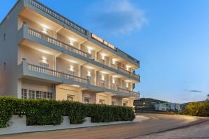 een groot wit gebouw met balkons in een straat bij Paradise Art Hotel in Ándros