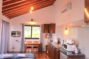 eine Küche mit Theke und einem Tisch mit Stühlen in der Unterkunft Beachscape Cottage in Fajã