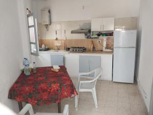 a small kitchen with a table and a white refrigerator at L'escale in Tunis
